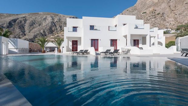 Moderner Poolbereich mit stilvollen Liegen und Palmen, umgeben von weißer Architektur und beeindruckender Bergkulisse – ideal zum Entspannen unter der griechischen Sonne.