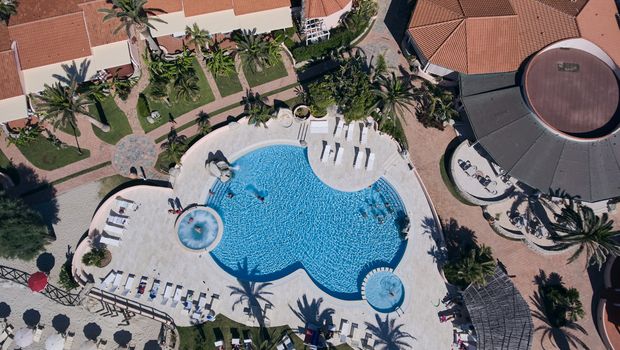 Großzügiger Poolbereich mit Whirlpool und Liegeflächen – perfekt für erholsame Stunden unter Palmen.