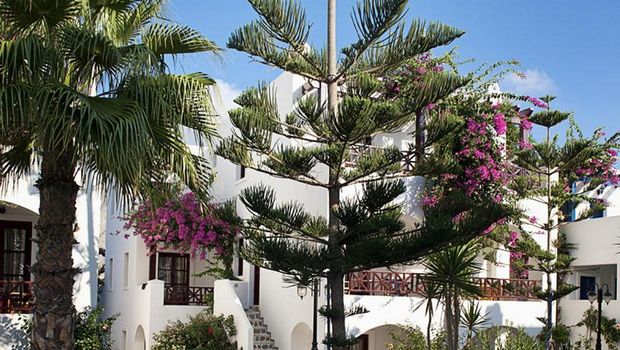 Mediterranes Hotel mit traditioneller Architektur, tropischer Bepflanzung und einladendem Rundpool – perfekt für entspannte Stunden unter der Sonne Griechenlands.