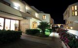Stimmungsvoll beleuchteter Hoteleingang bei Nacht – mediterranes Ambiente mit gepflegter Gartenanlage.