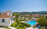 Charmante Hotelanlage inmitten grüner Hügel mit gepflegtem Garten, mediterraner Architektur und einladendem Poolbereich – ideal für entspannte Urlaubstage in idyllischer Umgebung.