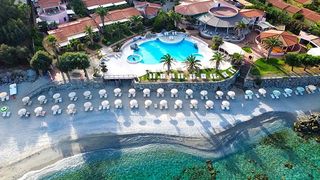 Traumhafte Lage direkt am kristallklaren Meer – der feine Kiesstrand mit eleganter Liegenreihe lädt zum Sonnenbaden und Entspannen ein.
