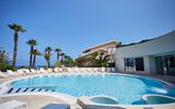 Ruhiger Poolbereich mit Palmen und gemütlichen Liegen – ideal für entspannte Stunden unter freiem Himmel.