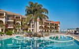Weitläufige Poolanlage mit eleganter Brücke, umgeben von tropischer Bepflanzung und blühenden Bougainvillea – ideal für entspannte Stunden unter südlicher Sonne.