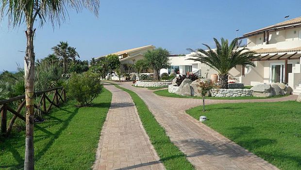 Weitläufige, gepflegte Gartenanlage mit mediterranem Flair und kleinen Wegen, die durch das Resort führen.