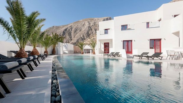 Moderner Poolbereich mit stilvollen Liegen und Palmen, umgeben von weißer Architektur und beeindruckender Bergkulisse – ideal zum Entspannen unter der griechischen Sonne.