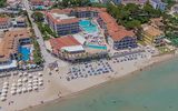 Luftaufnahme eines belebten Strandhotels mit großem Poolbereich, Sonnenschirmen am Strand und direkter Lage am klaren Meer.