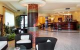 Heller Hotel-Loungebereich mit gemütlichen Sitzgruppen, stilvoller Mosaiksäule und eleganter Bar mit großer Getränkeauswahl – freundliches Ambiente mit modernen und klassischen Elementen.