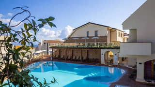 Moderner Hotelpool mit großzügiger Sonnenterrasse, gemütlichen Liegen und mediterranem Flair in zentraler Lage.