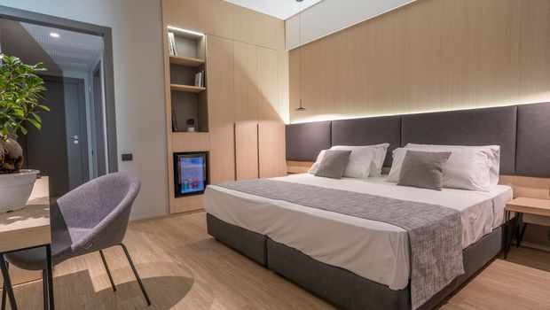 Modernes Doppelzimmer mit stilvollem Interieur, gemütlichem Bett, Schreibtisch und Minibar – ideal für entspannte Urlaubstage in elegantem Ambiente.